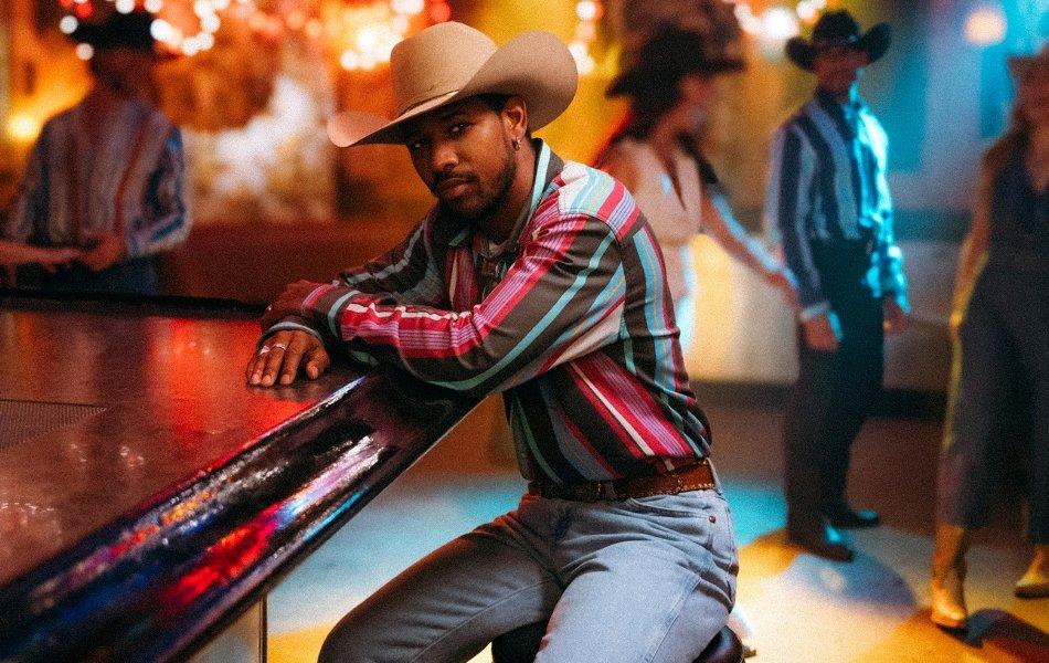 Guy sitting alone at a dimly light bar wearing brushpopper