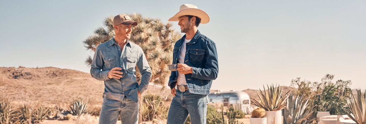 Two men in the desert, talking and drinking coffee