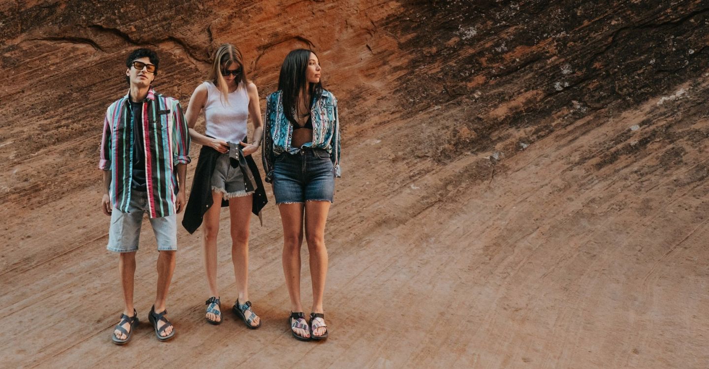 Two girls and a guy standing out west on a rock monolith - Shop Wrangler x Chaco