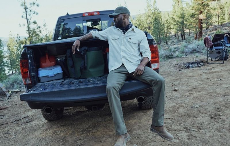 Guy sitting in the bed of his truck looking at a cooler.