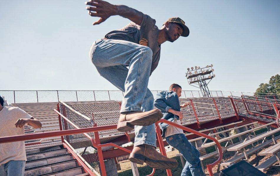 a man jumping over a stadium railing wearing Wrangler Toughlite.