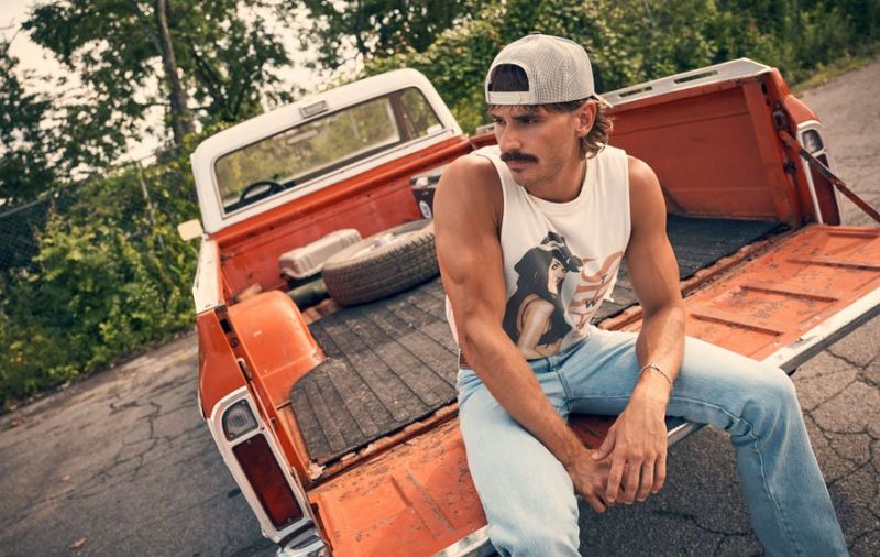 Two guys sitting in the bed of a red truck.