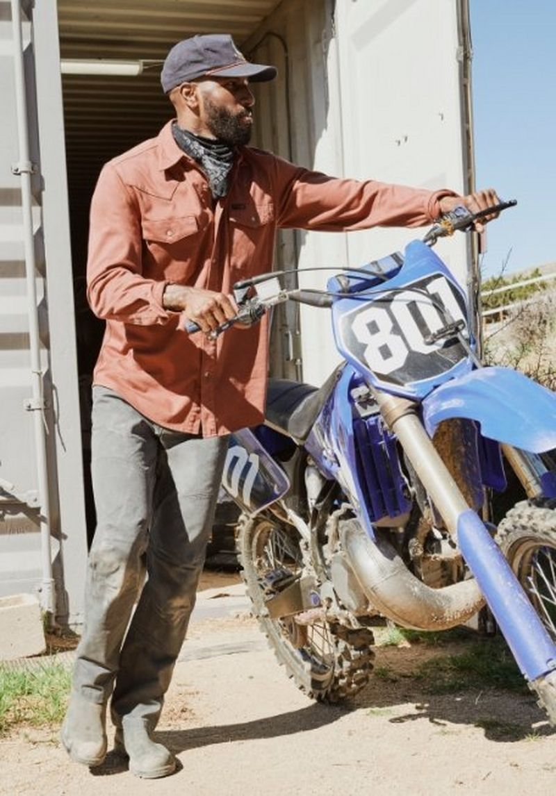 Guy holding onto a dirt bike, ready to ride.