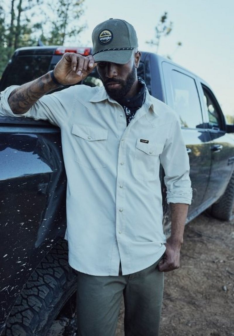 Guy leaning against a truck, wearing a performance shirt.