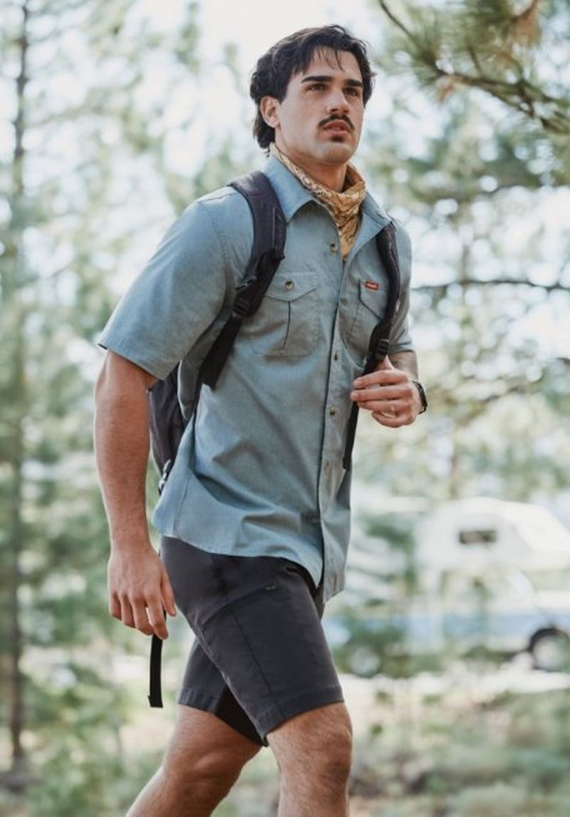 Guy hiking down a sunlit trail wearing performance shorts.