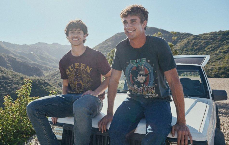 Two guys in tee shirts and jean sitting on the hood of a car - Five Star Jeans