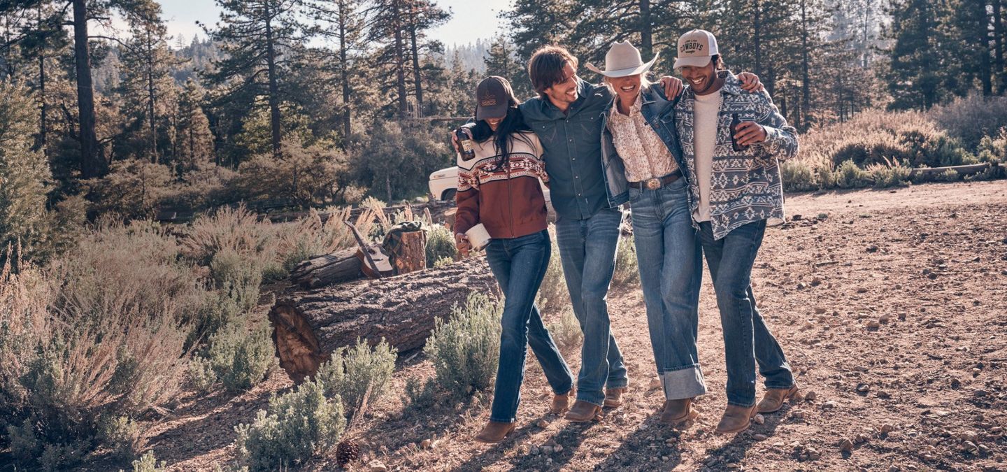 Guys and girls wearing fall clothes, gathered round a vintage truck in the woods. Shop Fall