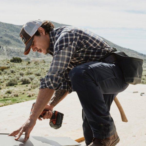 man using a power drill wearing Wrangler workwear and a baseball cap