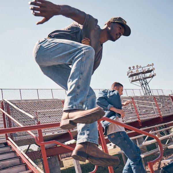 a man jumping over a stadium railing wearing Wrangler Toughlite