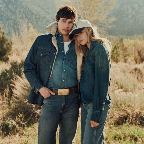 man and woman standing in a field wearing denim on denim looking into the camera