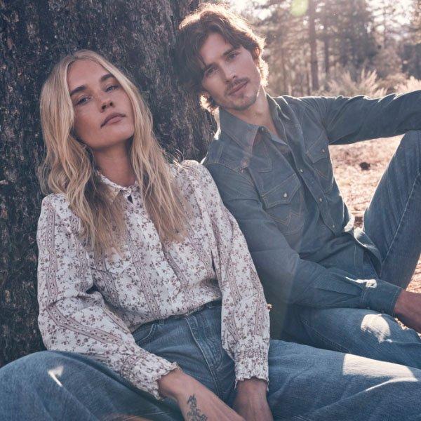 man and woman sitting beside a tree wearing Wrangler apparel