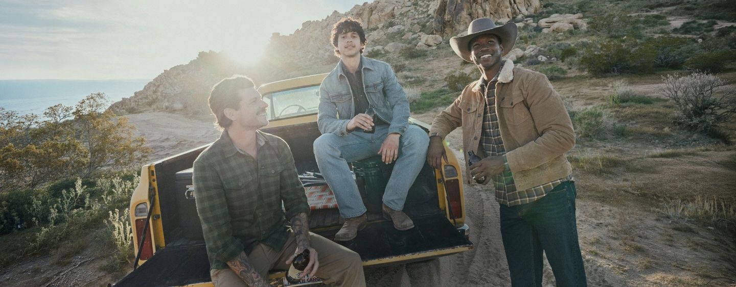Guys wearing fall clothes, gathered round a vintage truck in the woods. Shop Fall