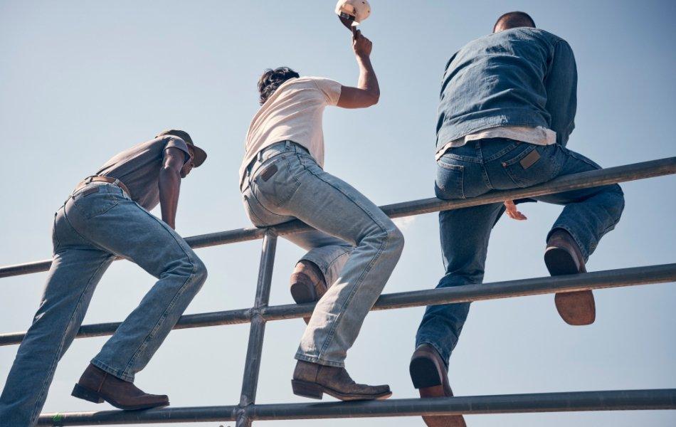 back shot of three men sitting on a fence wearing Wrangler Toughlite jeans.