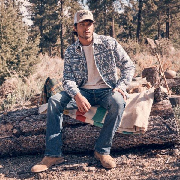 man sitting on a log wearing Wrangler jeans.