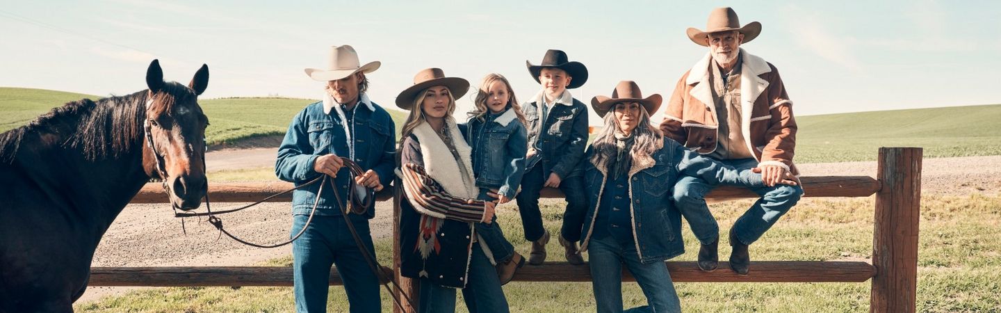 Group of grandparents, parents and children wearing cowboy hats and sherpa, sitting at the ranch.