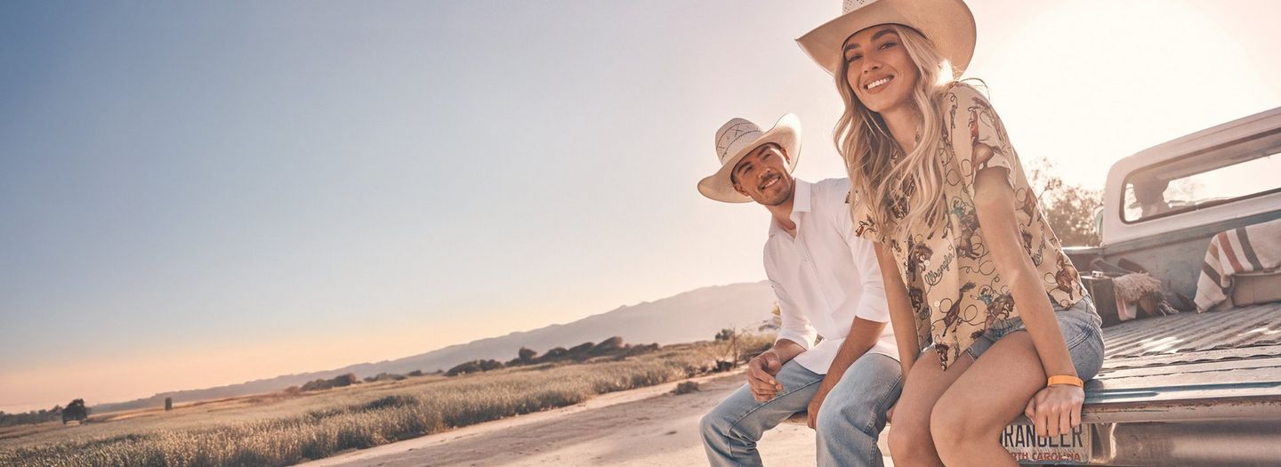A guy and girl sitting in the bed of a truck in the desert