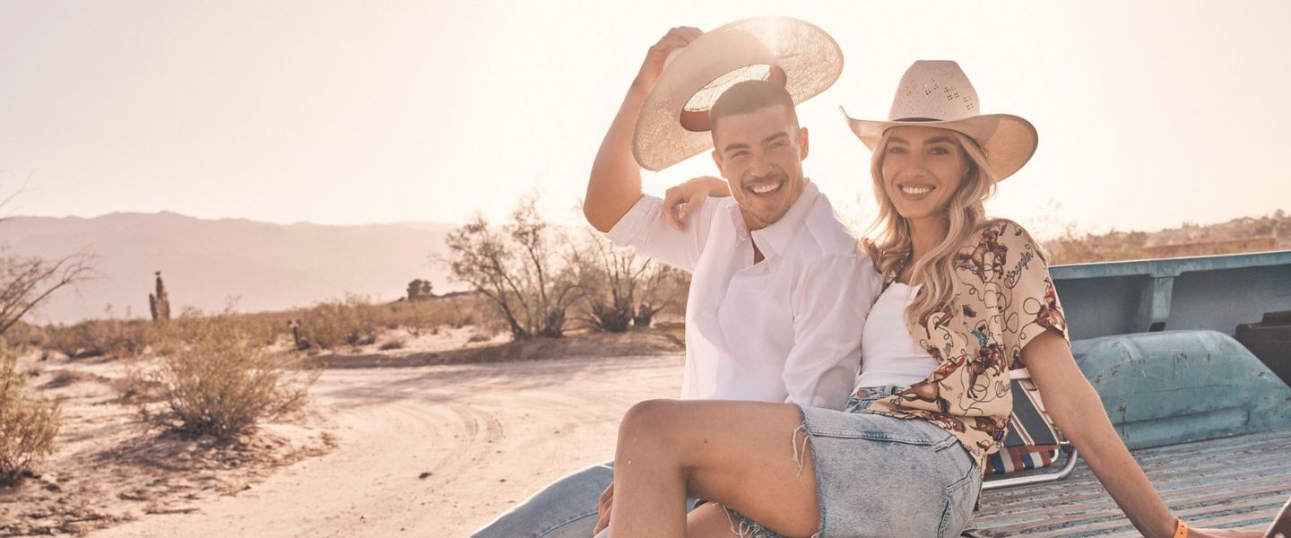 A guy and girl sitting in the bed of a truck in the desert