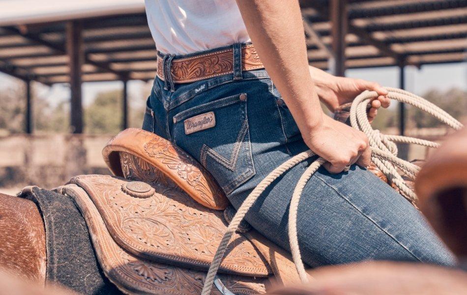 girl in a cowboy hat and denim skirt looking at the camera