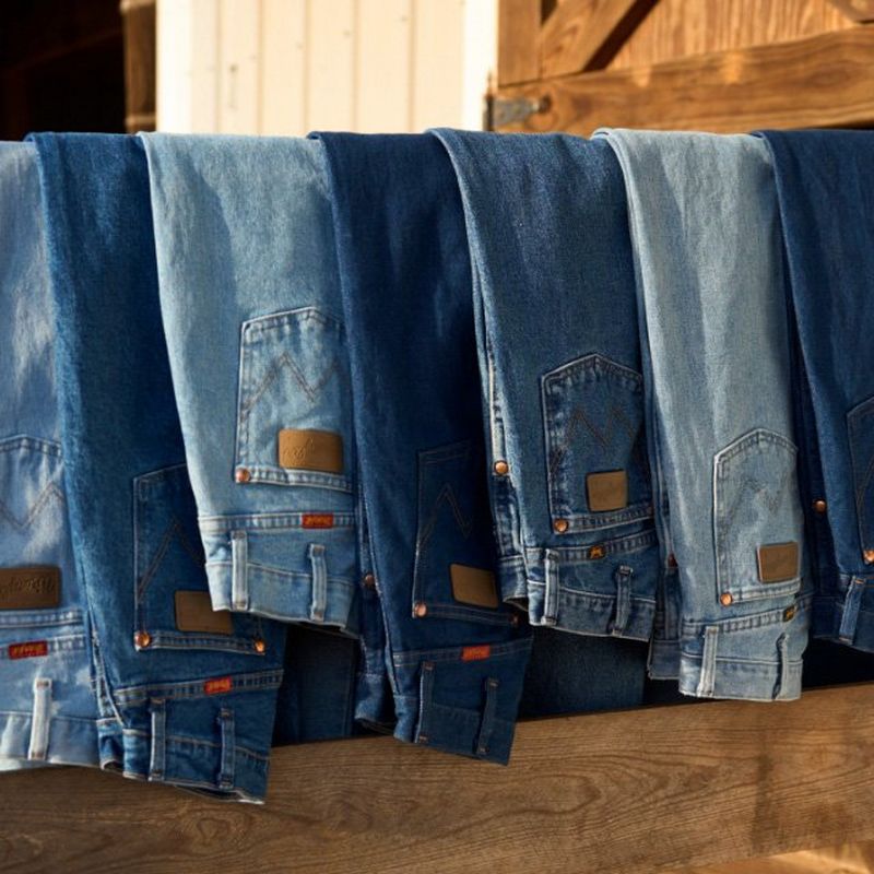 Pairs of men's jeans draped over a fence