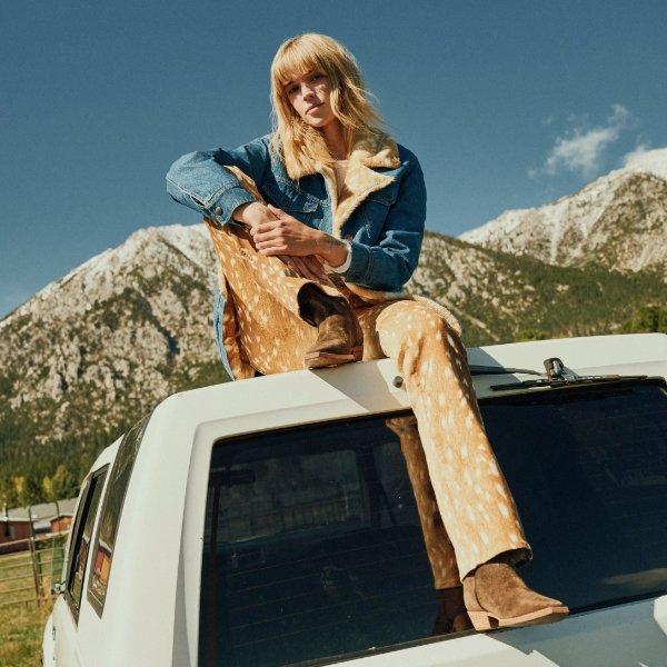 Woman sitting on the top of a truck wearing Wrangler Fawn Jeans