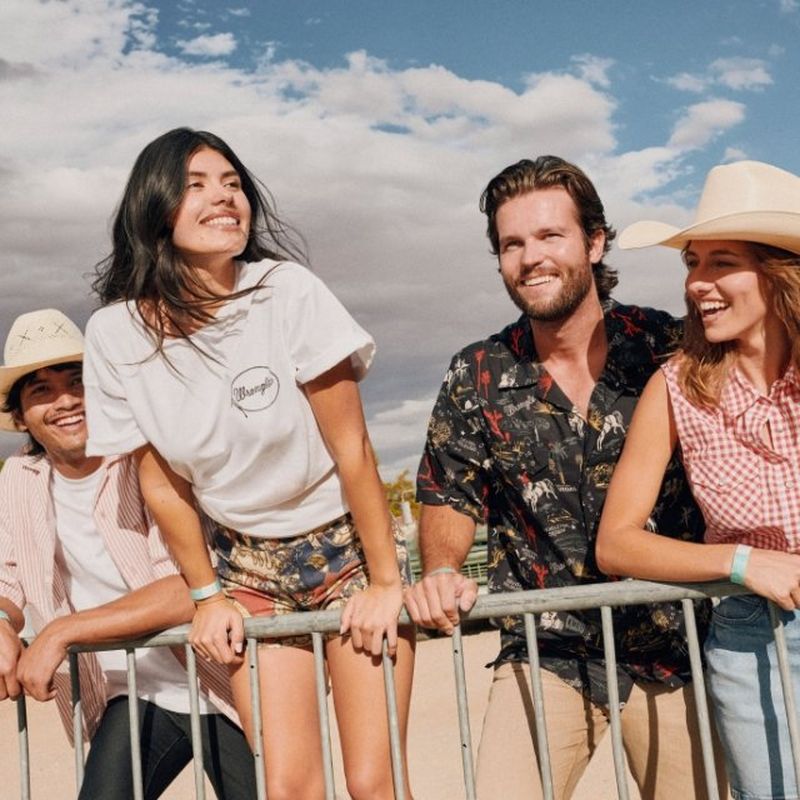 Group of people leaning against a barricade at an outdoor music festival.