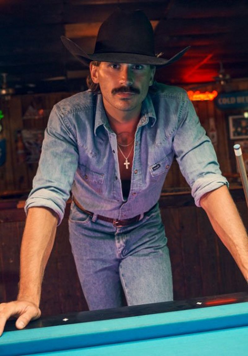 Guy leaning over a pool table wearing a western snap shirt.