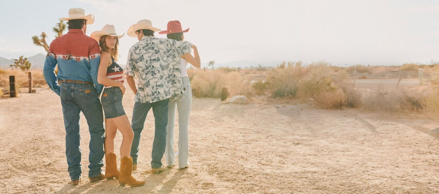 Group of cowboys and cowgirls standing in the desert, one girl looking back at the camera - Summer Styles
