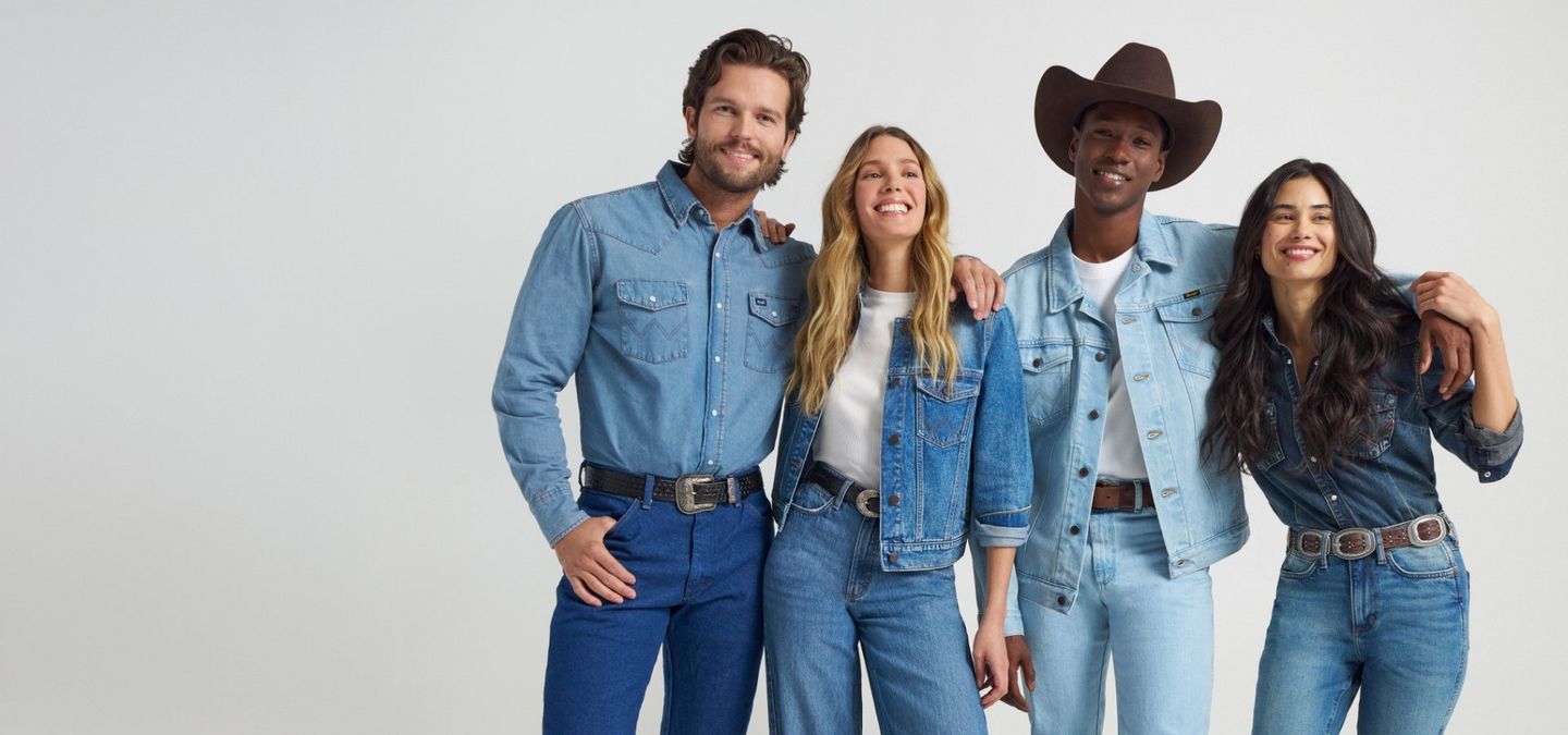 Group of people locking arms, smiling at the camera in a studio shoot on grey background - Join Wrangler Rewards