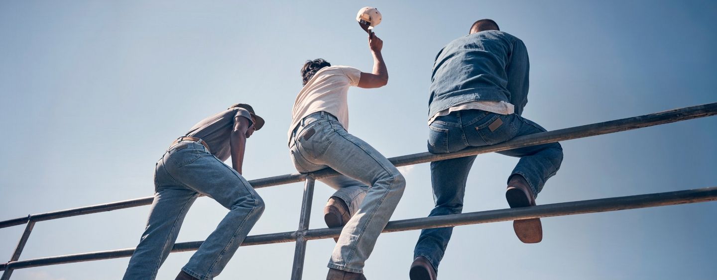 Guy wearing Wrangler Toughlite, jumping out of a cow pen.