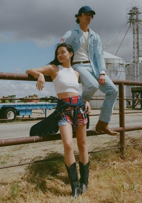 man and a woman sitting on a fence looking into the distance.