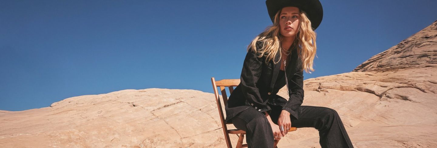 Women wearing a cowboy hat, standing in the desert. Wrangler x Kendra Scott