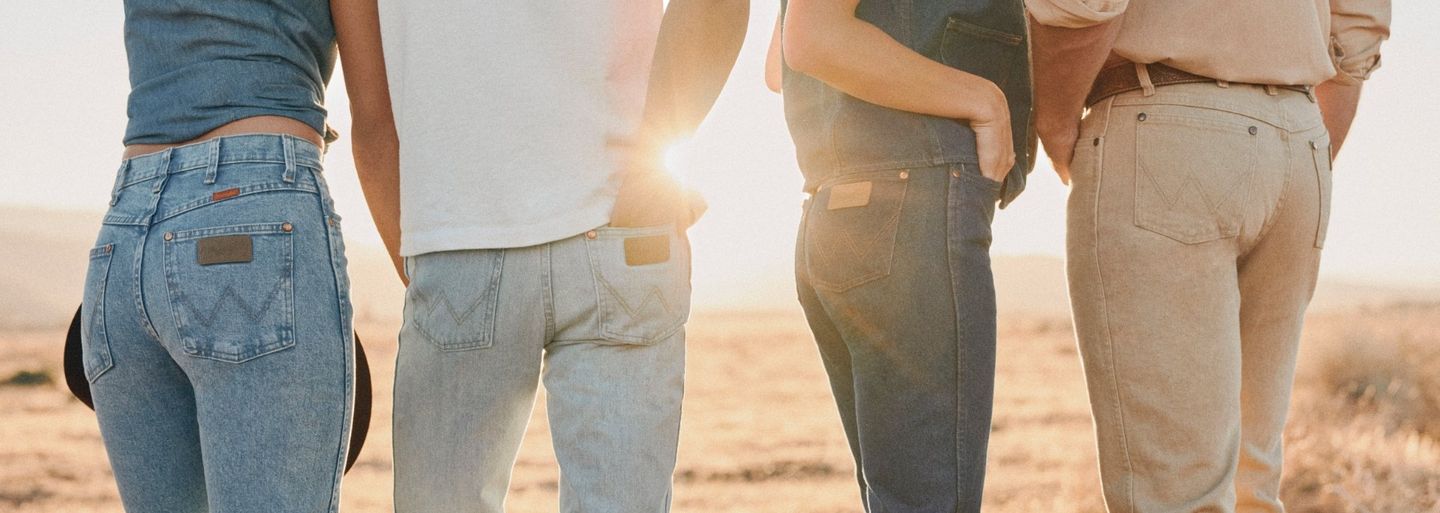 Group of people standing, facing away from the camera, cropped on their butts showing the Wrangler patch on their jeans.
