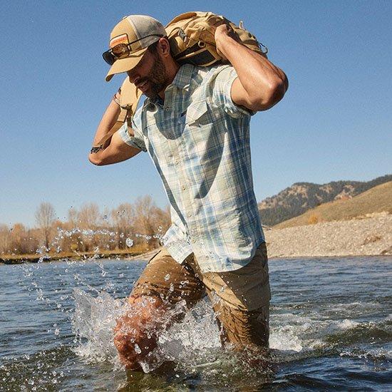 Guy backpacking through a river